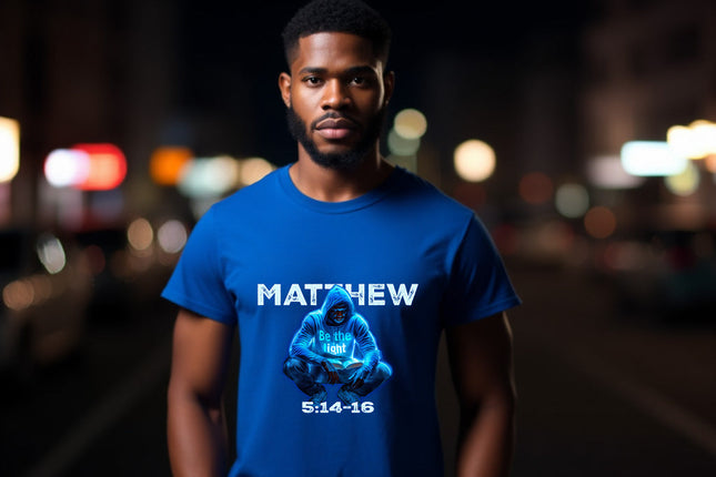 Man wearing a blue t-shirt with a graphic and text, standing on a street at night.