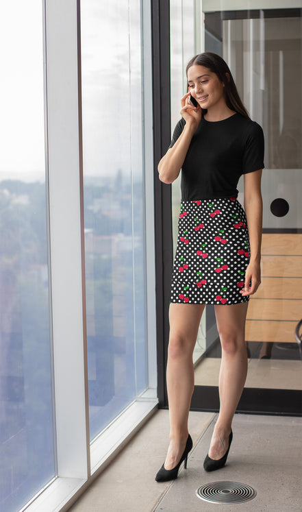 Woman in a black top and patterned skirt standing by a large window with a cityscape view.