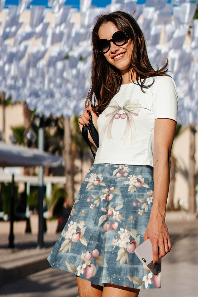 Woman wearing a white top and floral skirt with sunglasses, standing in front of a decorative wall.