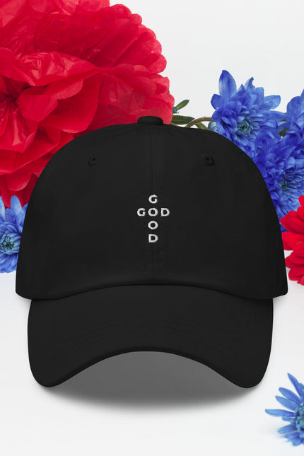 Black cap with 'G O D is good' text surrounded by red and blue flowers on a white background