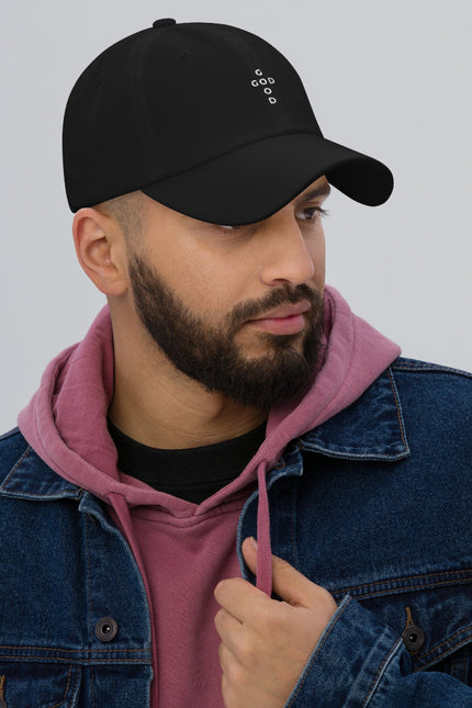 Man wearing a black cap, pink hoodie, and blue denim jacket on a gray background