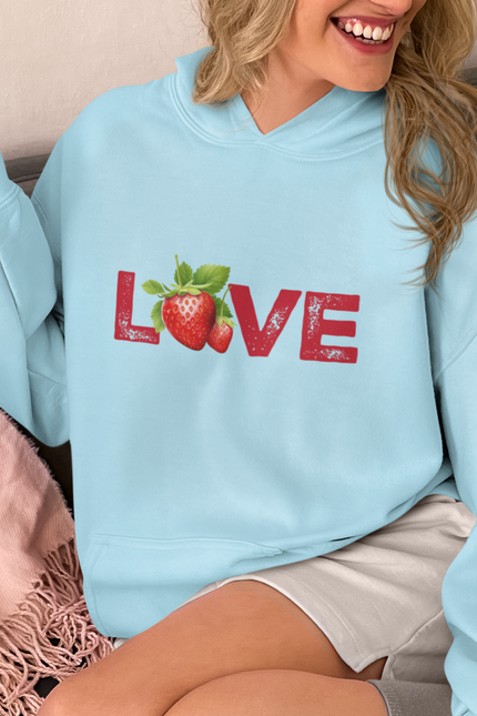 Person wearing a light blue hoodie with 'LOVE' and strawberry design, sitting on a couch.