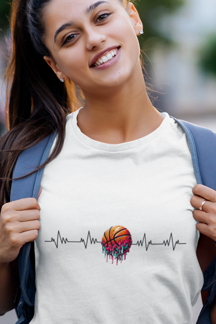 Woman wearing an ice grey t-shirt with a colorful heart and heartbeat line design, smiling outdoors.