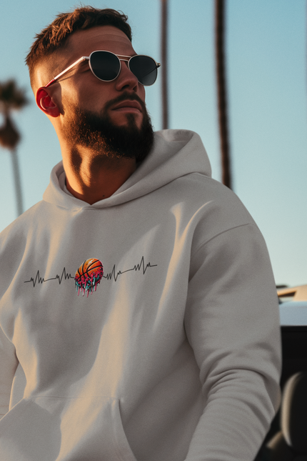 Man wearing a light gray hoodie with a colorful design, sunglasses, and a blurred background of palm trees and sky.