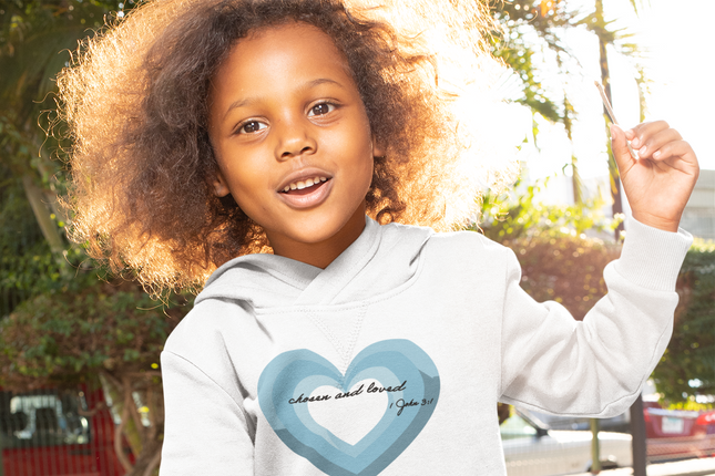 Child wearing a white hoodie with a blue heart design outdoors