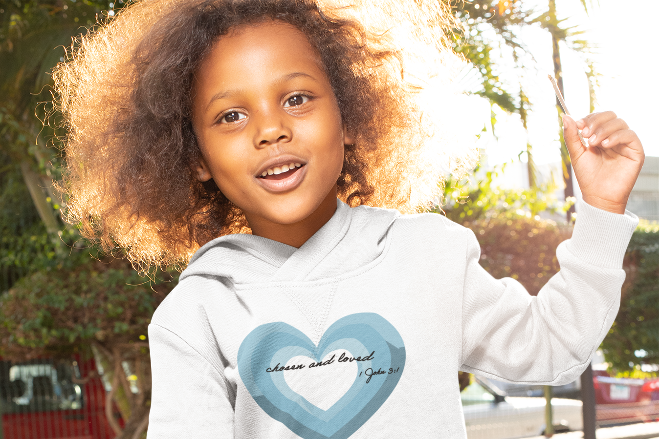 Child wearing a white hoodie with a blue heart design outdoors