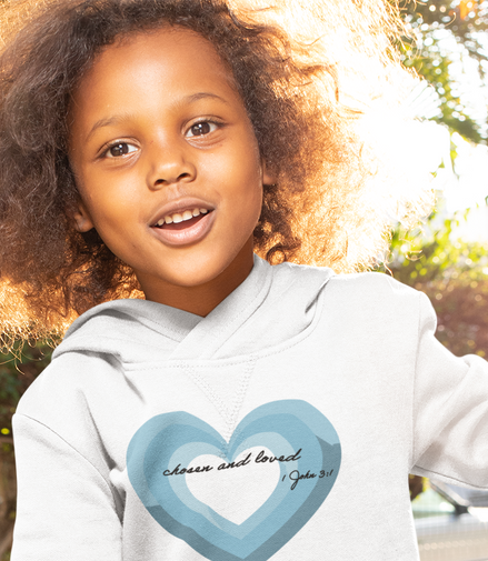 Child wearing a white hoodie with a blue heart design outdoors